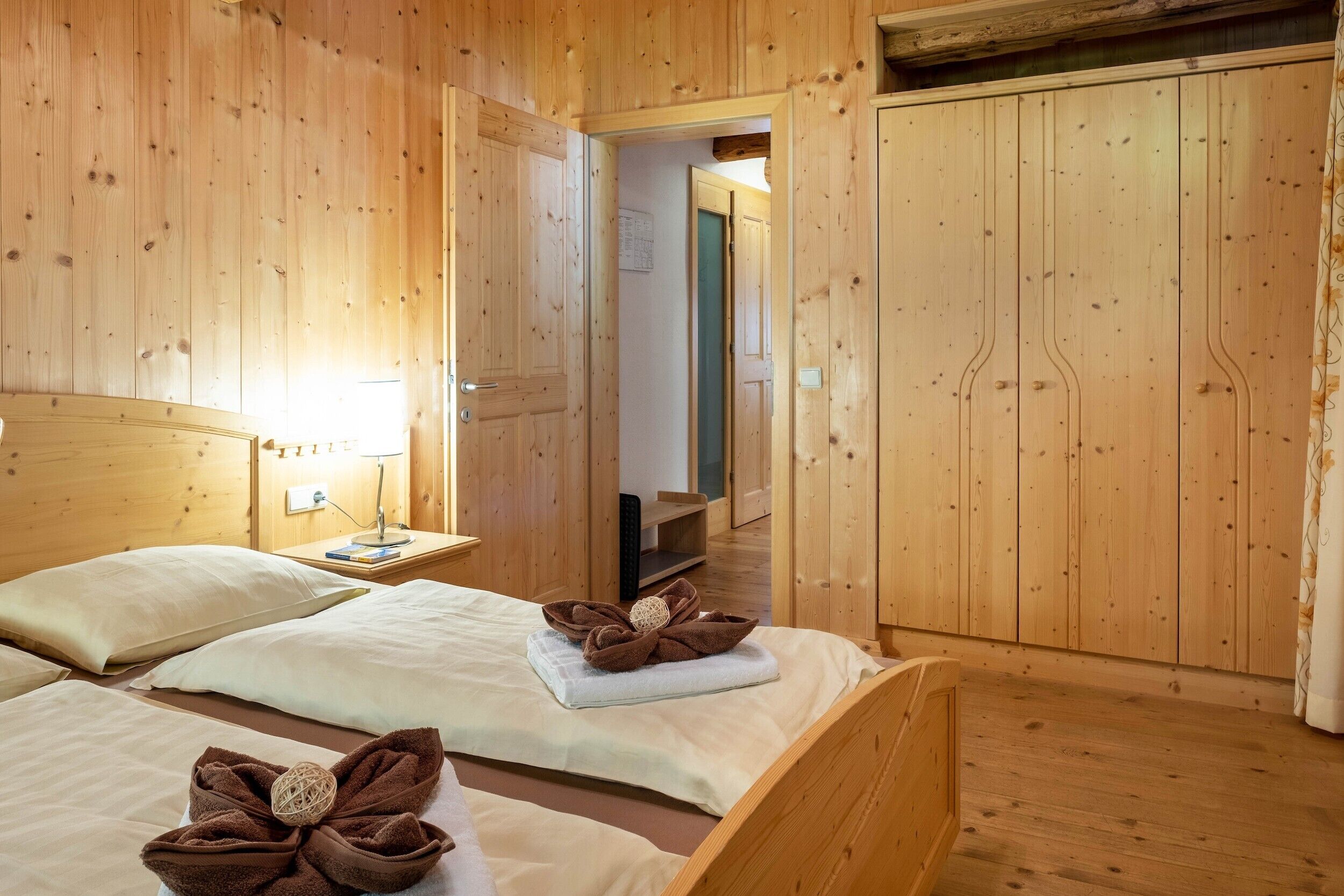 A wooden room with two beds, a nightstand, and a mirror.