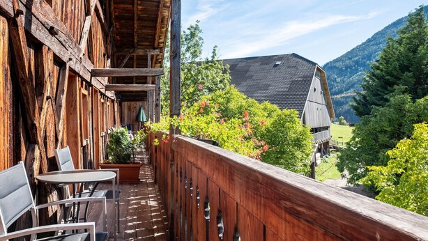 Un balcon en bois offrant une vue sur une montagne, avec une table et des chaises.