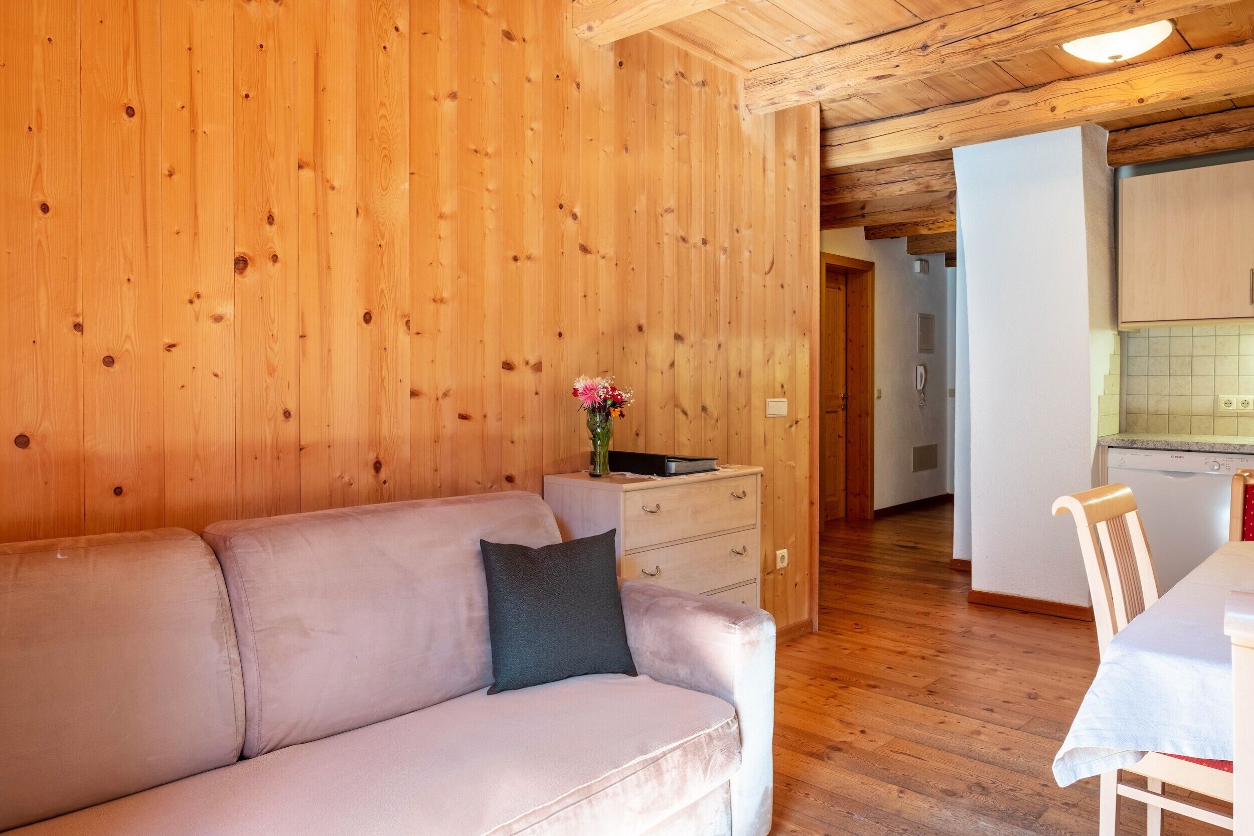 Ambiente interno in legno con divano, un tavolino e angolo cottura.