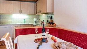 Une table à manger avec une bouteille de vin, des verres, un saladier de fruits et un couteau.
