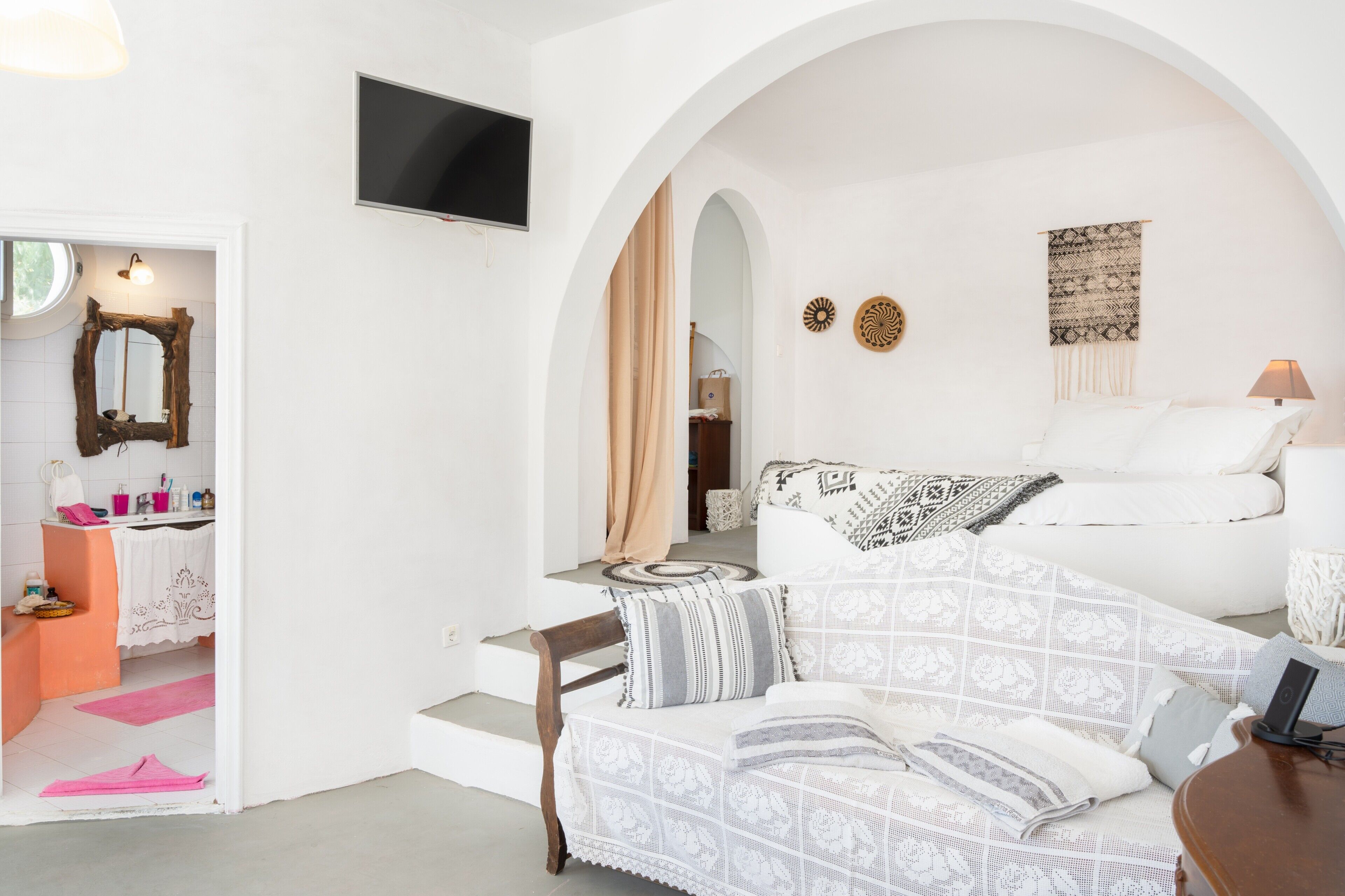 Una habitación moderna con un sofá blanco, un televisor y un tapiz estampado.