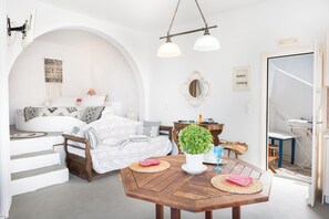 A modern living room with a sofa, dining table, and a potted plant.