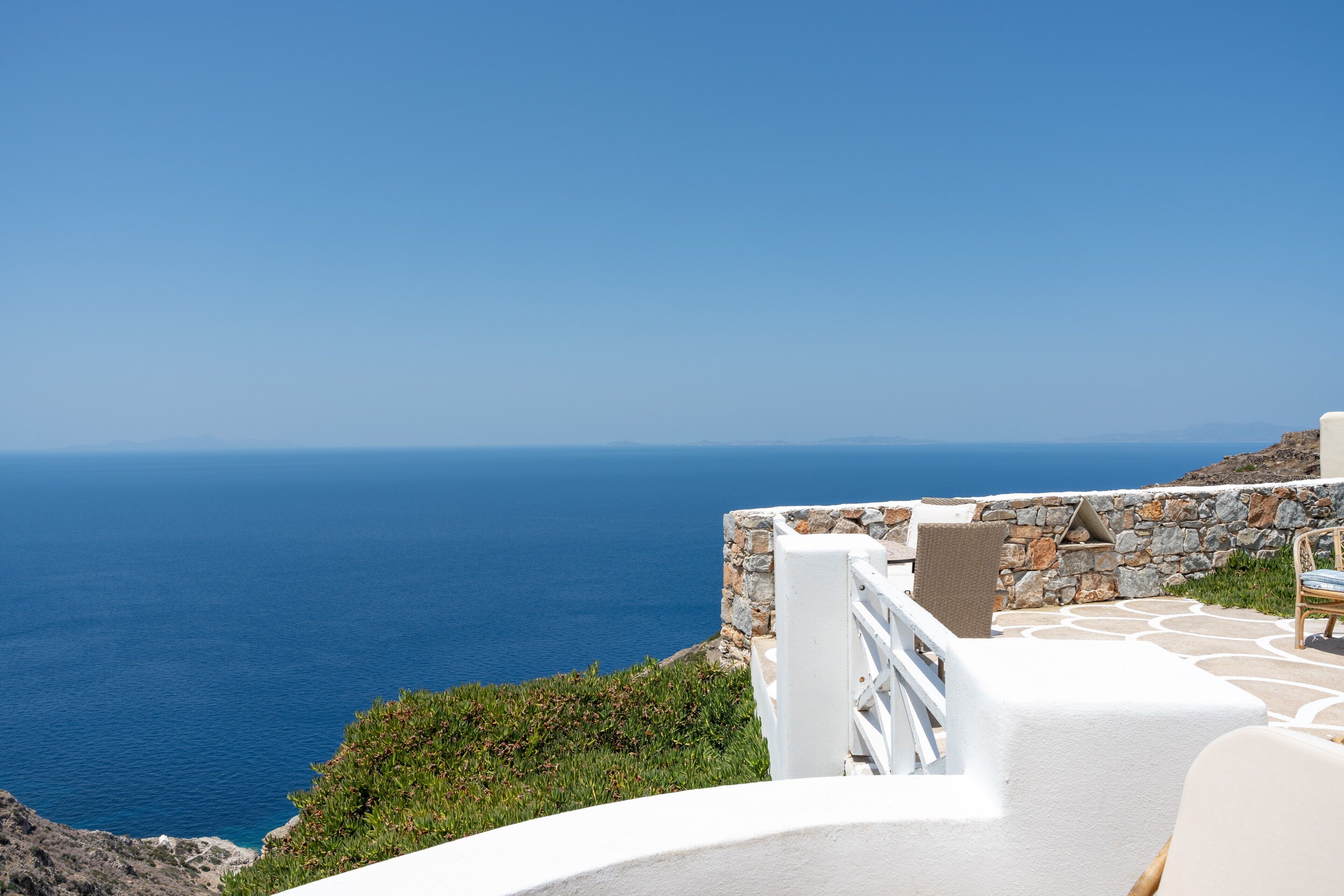 Une vue sur la côte, avec un mur de pierre et une balustrade blanche surplombant la mer.