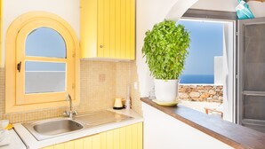 Une cuisine avec des meubles de couleur jaune, un évier et une plante en pot.