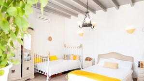 Une chambre avec deux lits, un lustre, des tables de chevet et une plante en pot.