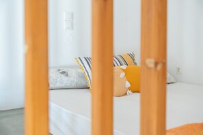 Un lit avec des oreillers, une structure en bois au premier plan et un interrupteur mural.