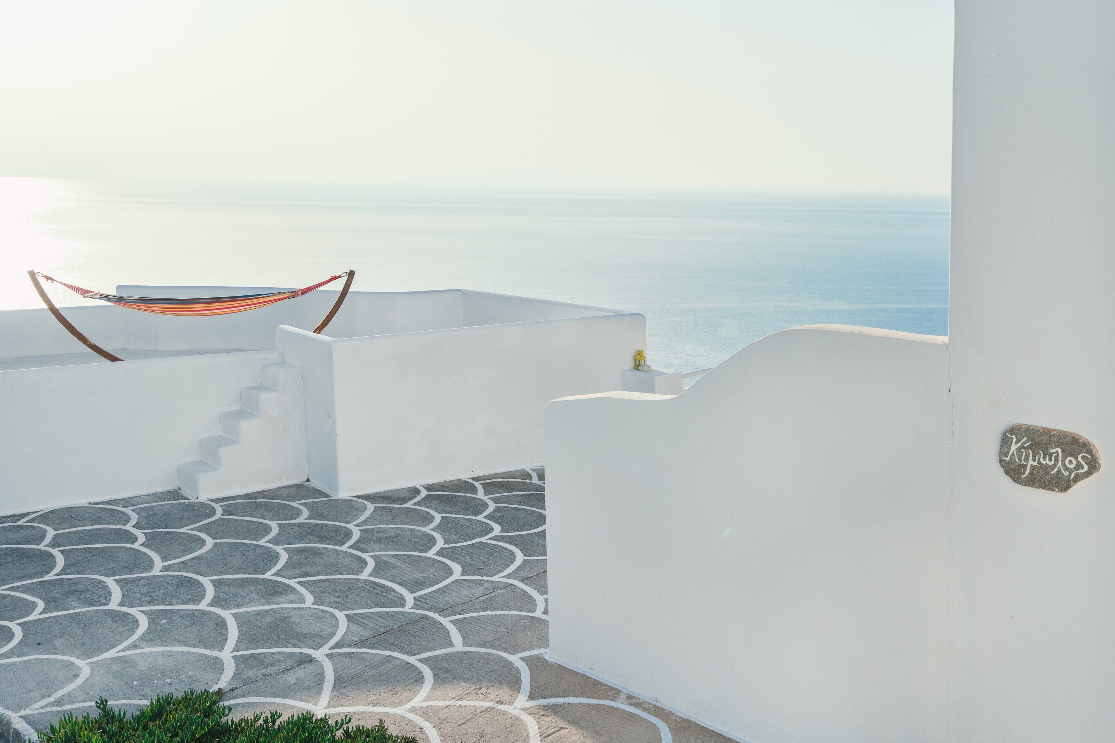 Un bâtiment aux murs blancs, doté d’un sol dallé imitant la pierre, d’un hamac et offrant une vue sur la mer.