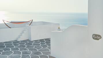 Un bâtiment aux murs blancs, doté d’un sol dallé imitant la pierre, d’un hamac et offrant une vue sur la mer.