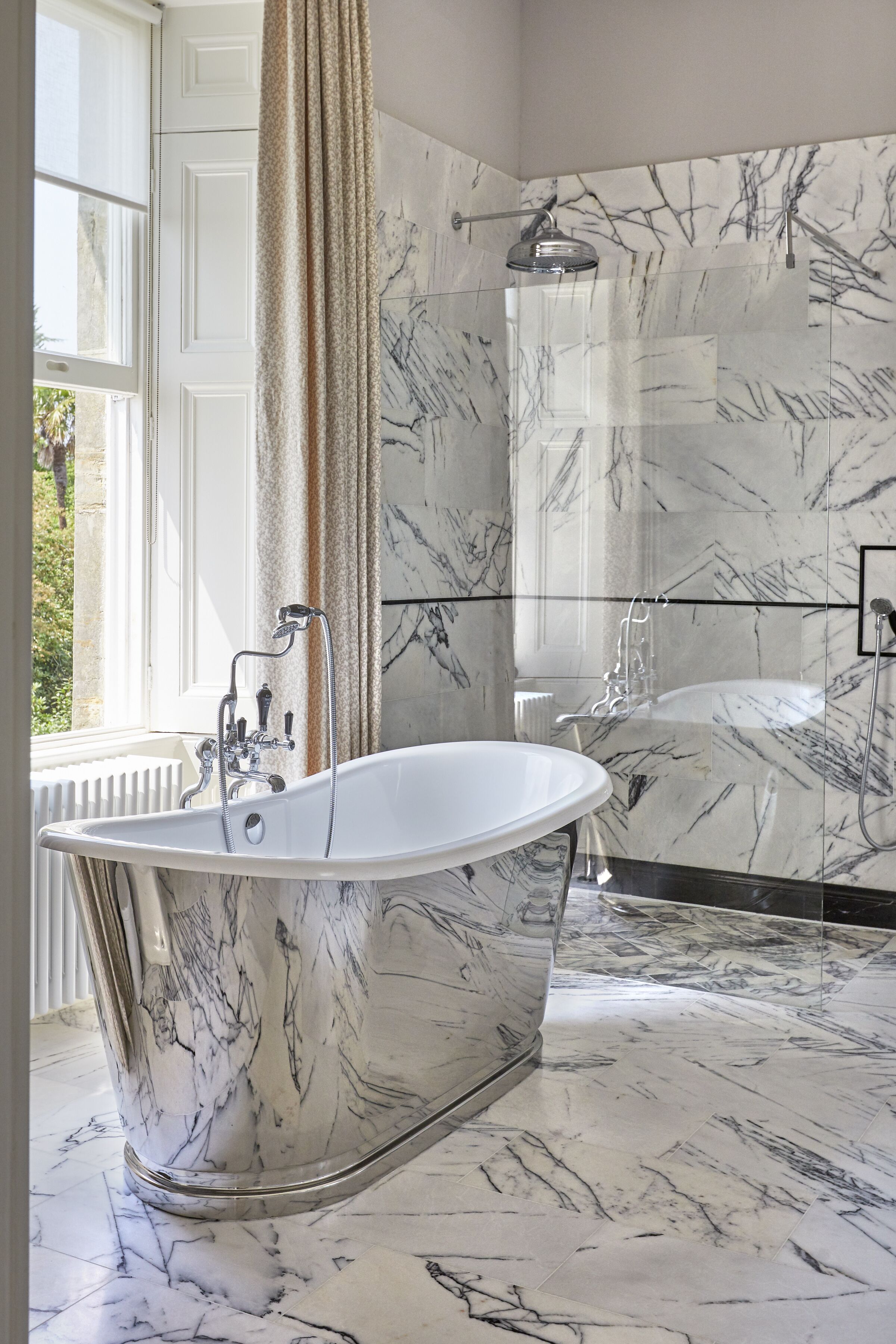 A bathroom with a freestanding bathtub, a shower, and marble flooring.
