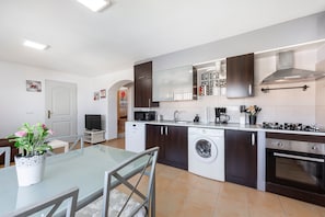 A modern kitchen with a dishwasher, washing machine, microwave, and stove.