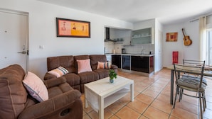 Un salon avec un canapé marron, une table basse blanche et un coin repas comprenant une table et des chaises.