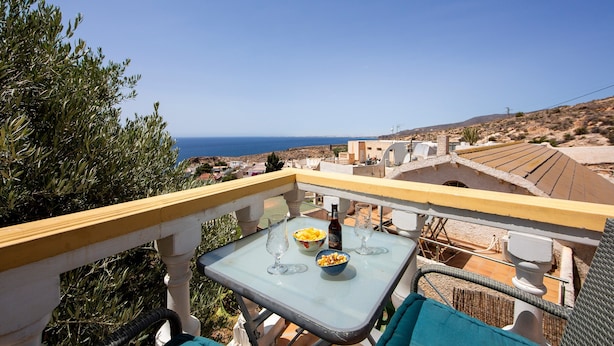 Un balcon avec une table, une bouteille et un saladier de fruits.