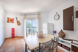 Comedor con una mesa, sillas, una guitarra, un reloj y vistas al exterior.