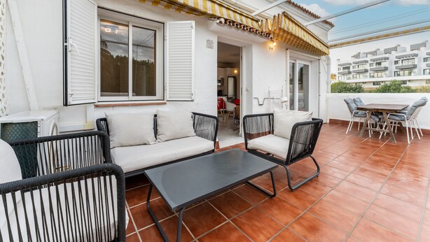 Una terrazza esterna con un divano, sedie e un tavolo.