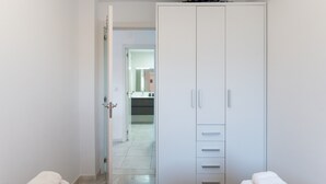 Camera da letto con due letti, un armadio e bagno parzialmente visibile attraverso una porta aperta.
