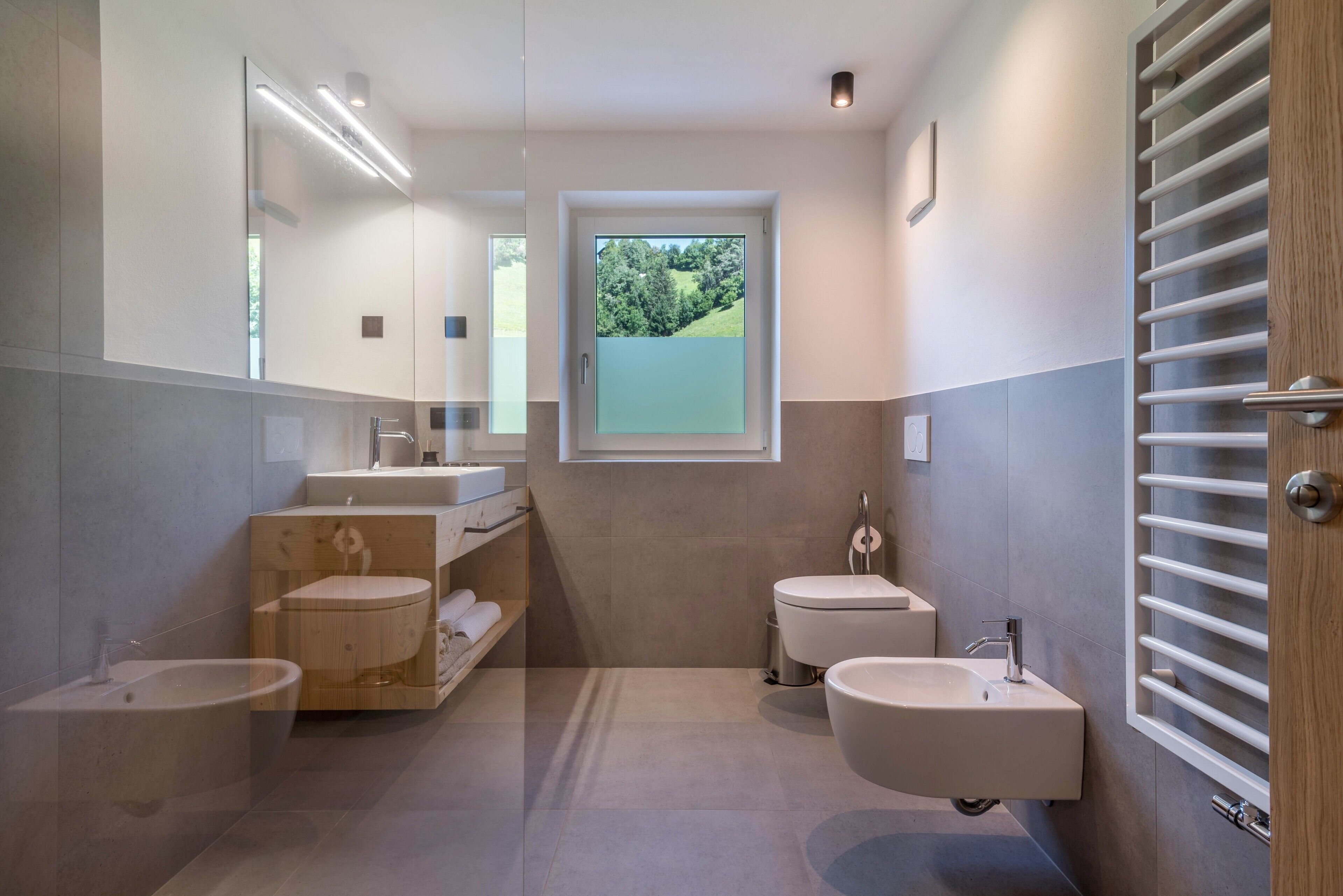 Un baño moderno con tocador, dos lavamanos, un bidé y un inodoro.