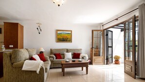 A living room with a sofa set, a coffee table, and a painting on the wall. - Vacation Home 'Puerto Chico B' with Sea View, Shared Pool & Wi-Fi (Playa Blanca)