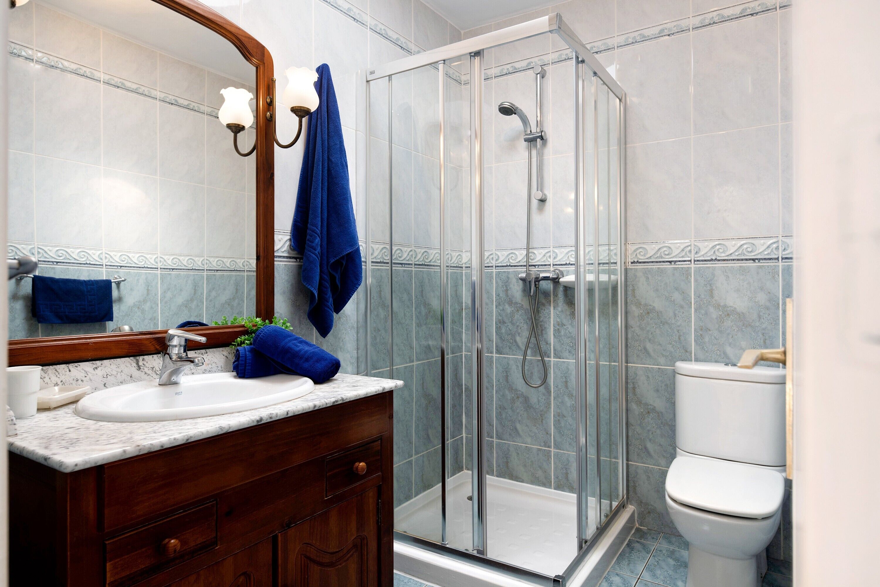 A bathroom with a glass-enclosed shower, a white sink, and a wooden vanity.