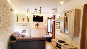 A modern living room with a sofa, a TV, a fireplace, and a wooden cabinet. - Villa 'Tore' with Sea View, Wi-Fi, and Air Conditioning (Quartu Sant'Elena)