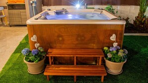 A hot tub with a wooden bench in front, surrounded by potted plants. - Villa 'Tore' with Sea View, Wi-Fi, and Air Conditioning (Quartu Sant'Elena)
