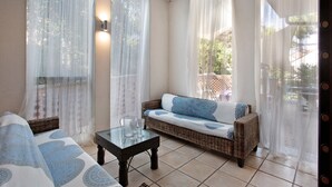 A room with a sofa, a glass-top table, and sheer curtains. - "Villa La Palmetta" with Pool, Terrace & Wi-Fi (Peschiera Borromeo)