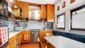 A modern kitchen with wooden cabinets, a dishwasher, and a dining area with a table and chairs. - "Villa La Palmetta" with Pool, Terrace & Wi-Fi (Peschiera Borromeo)
