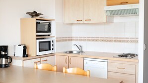 Eine Küche mit Mikrowelle, Backofen, Kaffeemaschine, Spüle und Geschirrspüler.
