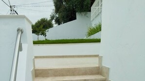 Un conjunto de escalones de concreto color beige con barandilla de metal, que conducen a una pared blanca.