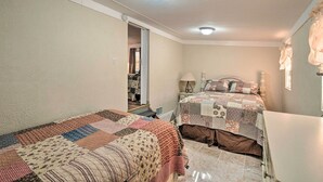 A bedroom with two beds, a nightstand, a lamp, and a door leading to a hallway. - Peaceful Satsuma Escape w/ Dunns Creek Access (Satsuma)