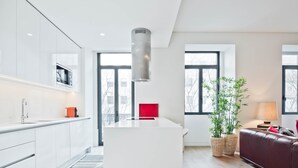 A modern kitchen with white cabinets, a central island, and a hanging light fixture. - Av. Liberdade 4 - Duque de Palmela (Lisbon)