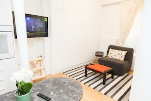 Relax in this stylish living room with a flat-screen TV, comfortable sofa, and a small side table.
