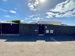 A parking area with a stone wall and a building with a white facade.