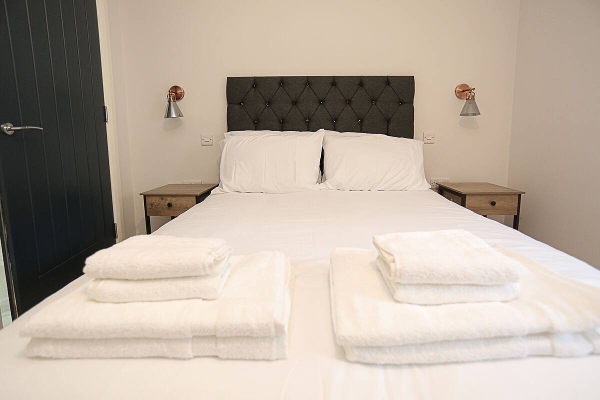 A neatly made bed with two pillows and two nightstands on either side.