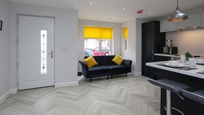 Een moderne keuken met een visgraatvloer, een zwart-geel kleed en een eethoek met een witte tafel en stoelen.