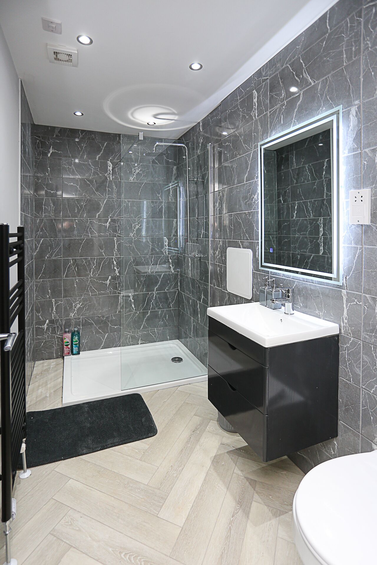 A modern bathroom with a walk-in shower, a vanity with a mirror, and a toilet.