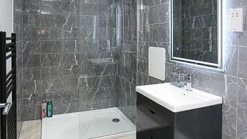 A modern bathroom with a walk-in shower, a vanity with a mirror, and a toilet.