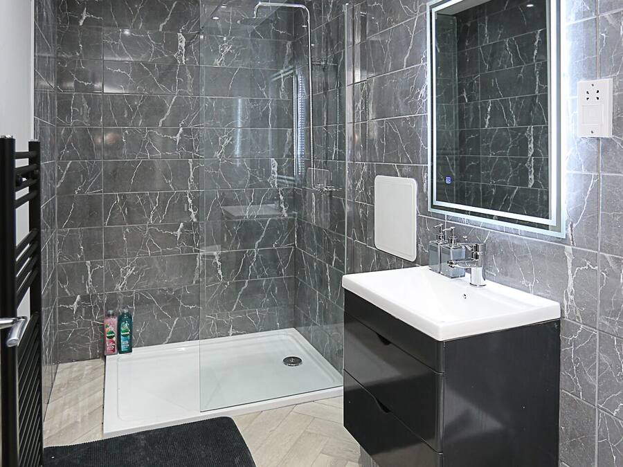 A modern bathroom with a walk-in shower, a vanity with a mirror, and a toilet.