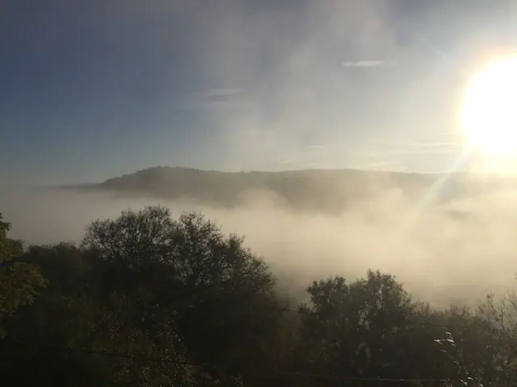 Un paysage avec une chaîne de montagnes baignée de soleil et un premier plan brumeux.