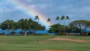 Un campo de golf con vista al océano y un arcoíris.