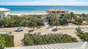 A beachfront property with a large house, a paved driveway, and a parked van.