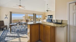 A kitchen with a granite countertop, wooden cabinets, and a dining area with a table and chairs.