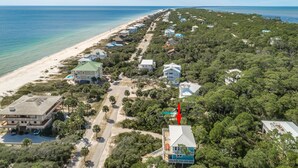 An aerial view of a coastal residential area with houses, a beach, and a clear sky.