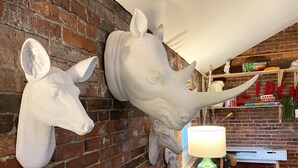 Um quarto com parede de tijolos, um sofá e duas cabeças de animais penduradas.