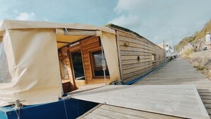 Een houten boot met een afgedekt dek en een ingang naar de kajuit.