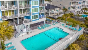 Un hôtel à plusieurs étages doté d’une grande piscine, d’un espace extérieur aménagé et de balcons.