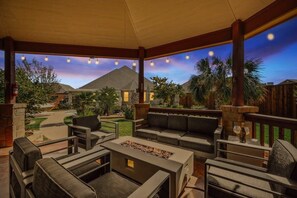 Un patio al aire libre con un brasero, zona de estar y luces colgantes.