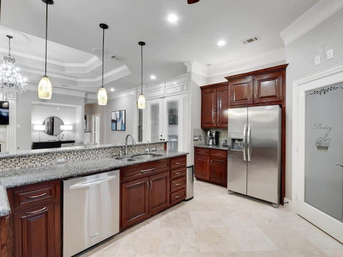 A modern kitchen with a granite countertop, stainless steel appliances, and wooden cabinets.