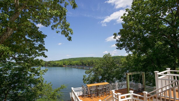 A wooden deck with white railings overlooking a lake, surrounded by trees. - Sunset Cottage on Badin Lake, NC! (New London)