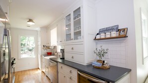 A kitchen with white cabinets, a black countertop, and a sign reading "Sunset Cottage 46985 Tall Whit Rd." - Sunset Cottage on Badin Lake, NC! (New London)