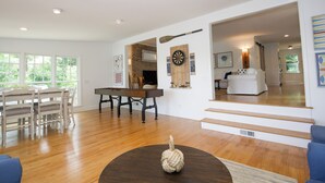 A spacious living room with hardwood floors, a dining area with a wooden table and chairs, and a staircase leading to another level. - Sunset Cottage on Badin Lake, NC! (New London)